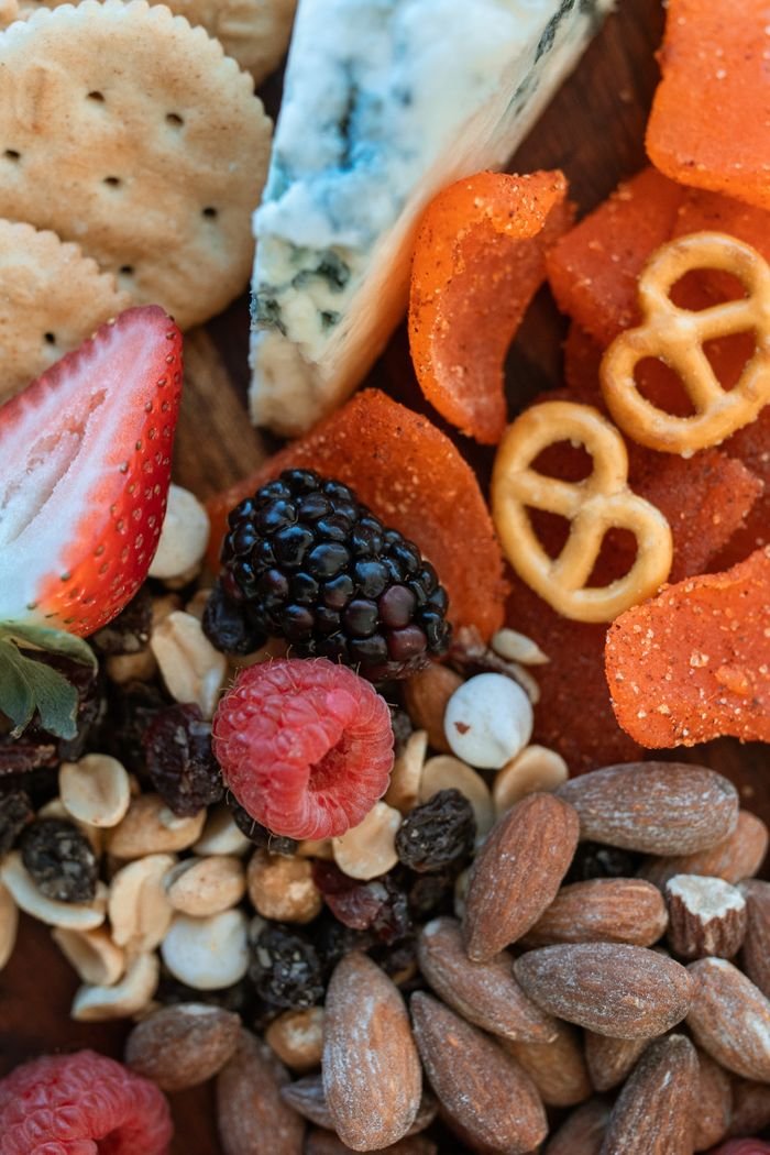 Close-up of a charcuterie board featuring a mix of cheese, fruits, nuts, and snacks.